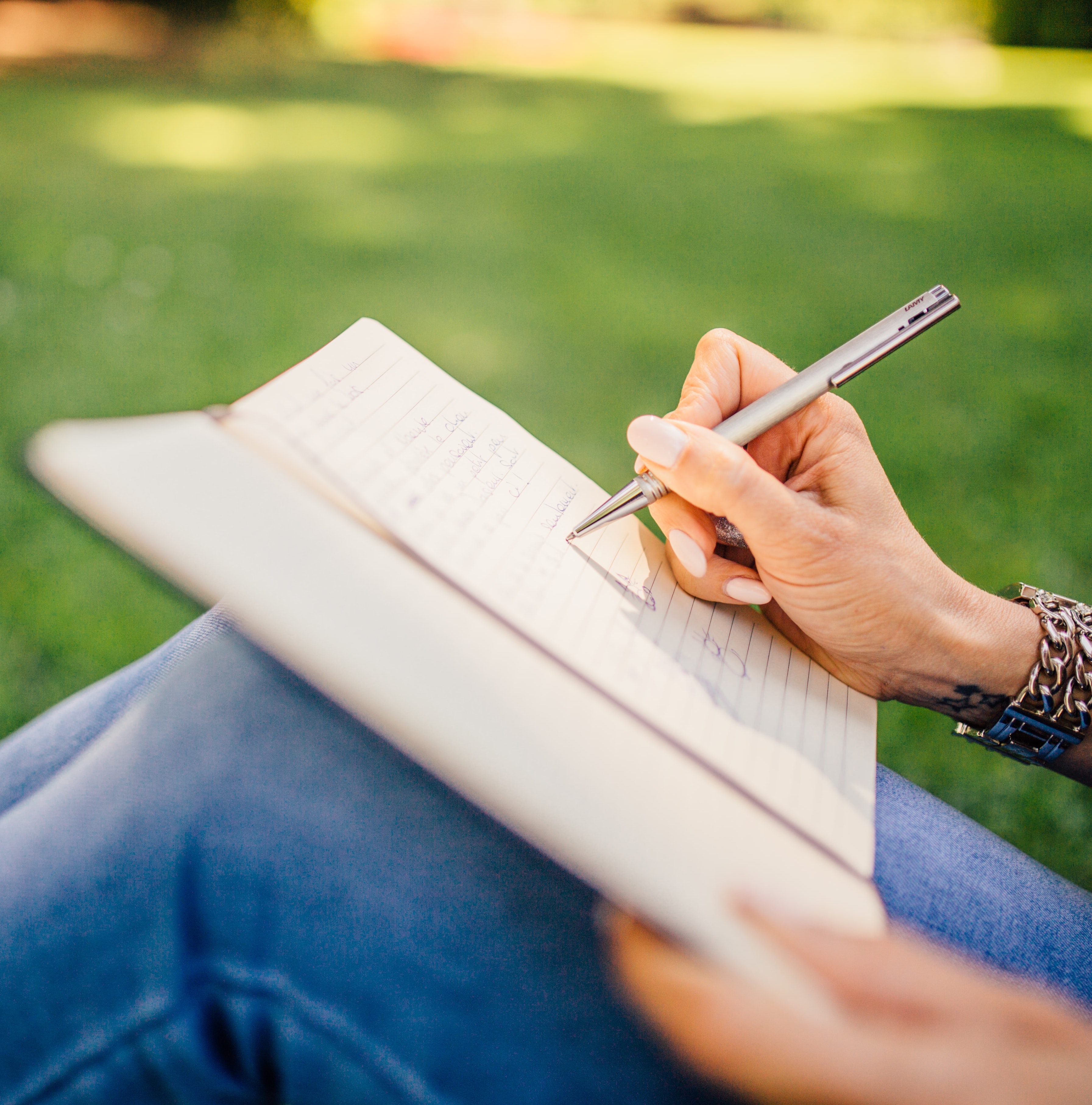 Stock image of a person
                                writing in a journal in a grassy field
