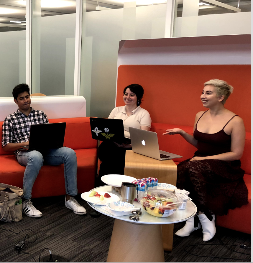 A photograph of Cara Marta
                                Messina, Ashley Clark, and Parth Tandel sitting on a couch during a meeting.
                                All three have laptops, but Cara is speaking to the group and Ashley
                                is laughing.